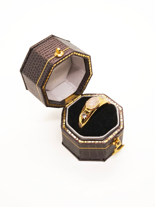 an opal crystal gold ring contained in a dark brown vintage ring holder box